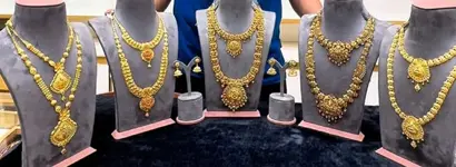 A row of gold harams and necklaces on grey busts over black velvet.