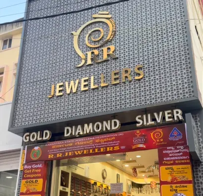 The RR Jewellers shopfront by day: a grey perforated screen with brass lettering over the door.